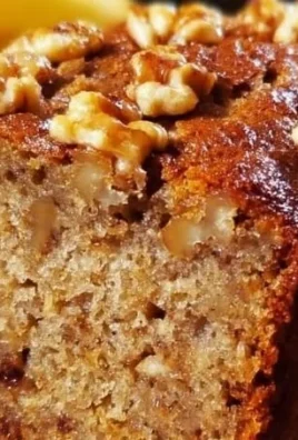 Sliced ultimate banana nut bread displayed on a plate with walnuts and bananas