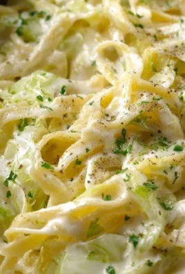 Plate of creamy Alfredo cabbage pasta garnished with herbs and grated cheese.