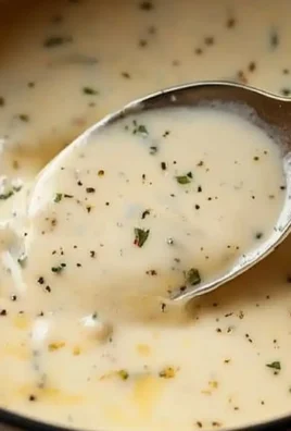 Creamy garlic parmesan sauce in a bowl with herbs on top