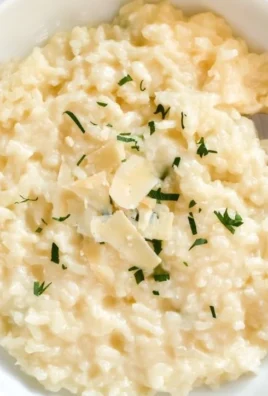 Creamy Parmesan Risotto served in a bowl with herbs and cheese garnished on top.