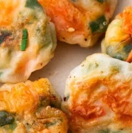 Shrimp and chive dumplings served on a plate, garnished with fresh herbs.