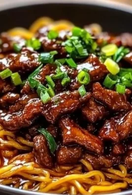 Delicious sticky beef noodles served on a plate with vegetables.