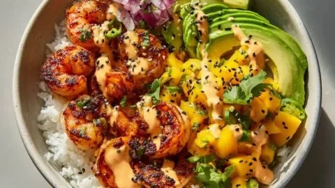 Delicious charred shrimp and avocado bowl garnished with fresh herbs.