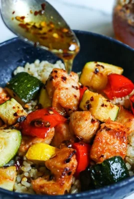 Delicious chicken rice bowl topped with homemade hot honey, garnished with fresh herbs.