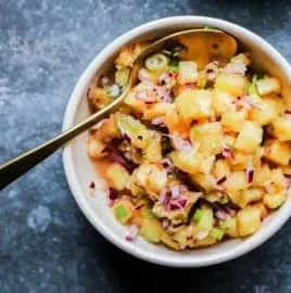 A vibrant bowl of grilled pineapple salsa with cilantro and red onion.