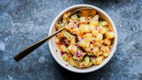 A vibrant bowl of grilled pineapple salsa with cilantro and red onion.