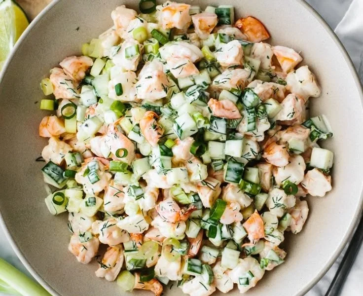 Healthy cucumber shrimp salad served in a bowl with fresh herbs and dressing.