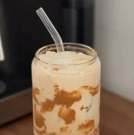 Delicious iced coffee served in a glass with ice and coffee beans