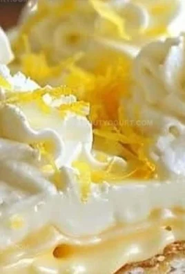 No-Bake Lemon Eclair Cake topped with lemon glaze and whipped cream on a plate