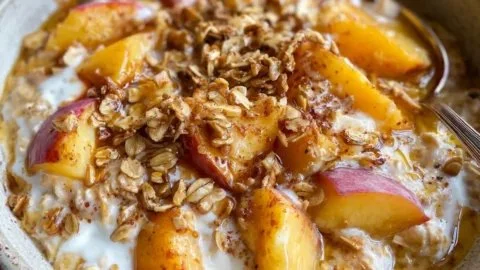 Bowl of Peach Cobbler Overnight Oats topped with fresh peaches and cinnamon
