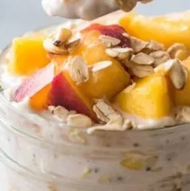 A bowl of Peach Overnight Oats topped with fresh peach slices and almonds.