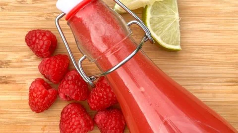 Raspberry Lime Probiotic Soda in a glass with vibrant colors and bubbles.