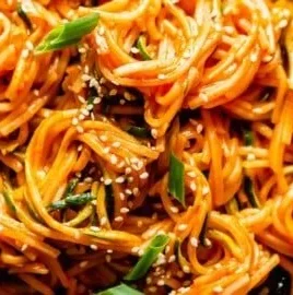 Bowl of saucy Gochujang Noodles topped with green onions