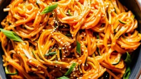 Bowl of saucy Gochujang Noodles topped with green onions