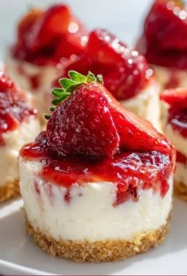 Delicious strawberry cheesecake bites on a white plate, topped with fresh strawberries.