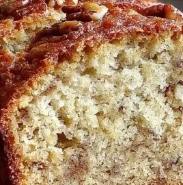 Slice of super moist banana bread on a wooden cutting board.