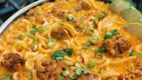 Delicious Thai-inspired coconut red curry chicken udon bowl with vibrant colors and spices.