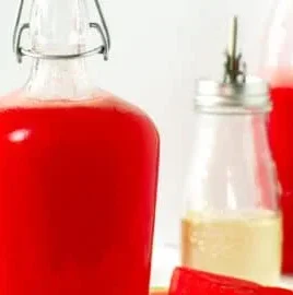 Homemade watermelon syrup in a glass bottle with fresh watermelon slices