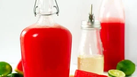 Homemade watermelon syrup in a glass bottle with fresh watermelon slices