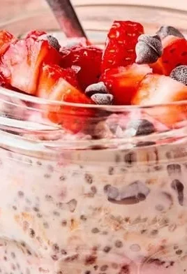Bowl of chocolate covered strawberry overnight oats topped with fresh berries.
