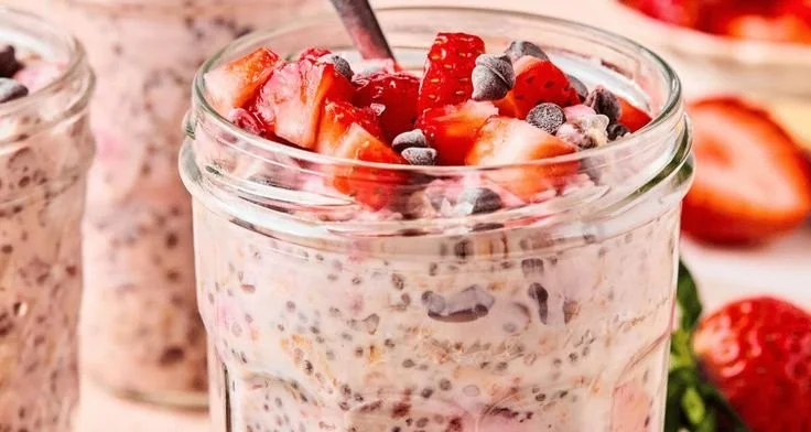 Bowl of chocolate covered strawberry overnight oats topped with fresh berries.