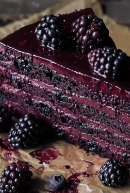 Slice of dark chocolate blackberry cake topped with fresh blackberries and chocolate shavings.