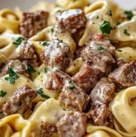 Delicious plate of Philly Cheesesteak Tortellini pasta topped with cheese and herbs.