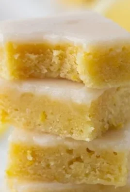Plate of freshly baked lemon blondies topped with a lemon glaze