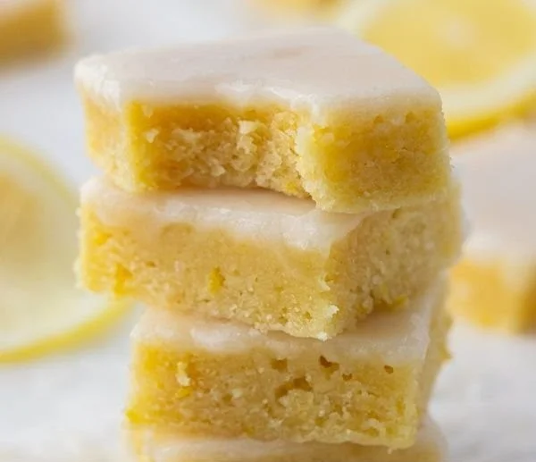 Plate of freshly baked lemon blondies topped with a lemon glaze