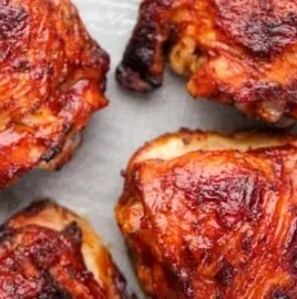 Delicious oven baked BBQ chicken thighs served on a plate with sauce