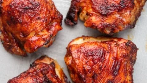 Delicious oven baked BBQ chicken thighs served on a plate with sauce