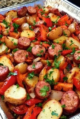 Oven-roasted sausages served with potatoes and colorful peppers on a plate.