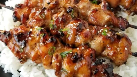 Delicious teriyaki chicken skewers on a grill, garnished with green onions.